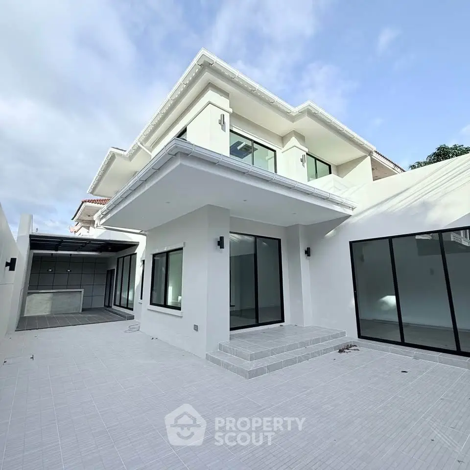 Modern two-story house with large windows and spacious outdoor patio.