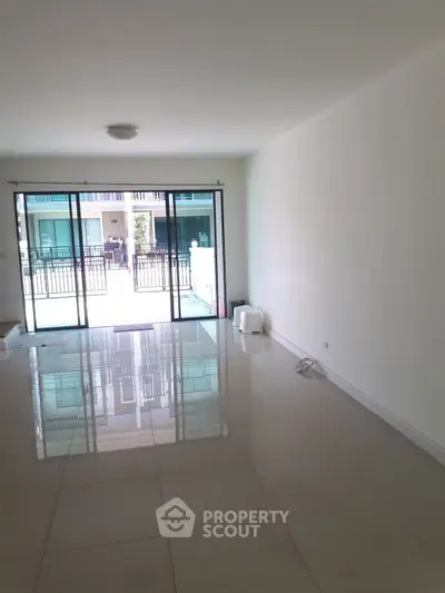 Spacious empty living room with large glass doors leading to a balcony, perfect for natural light.