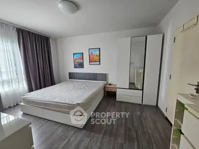 Spacious modern bedroom with sleek furniture and large window for natural light.