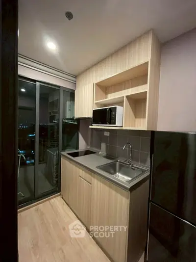 Modern kitchen with sleek cabinets and balcony view in urban apartment