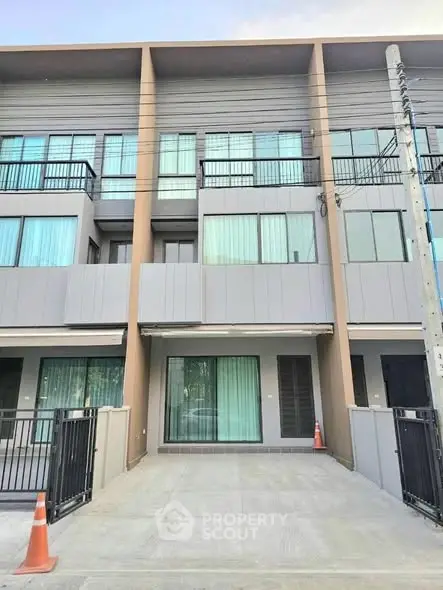 Modern townhouse exterior with large windows and gated driveway