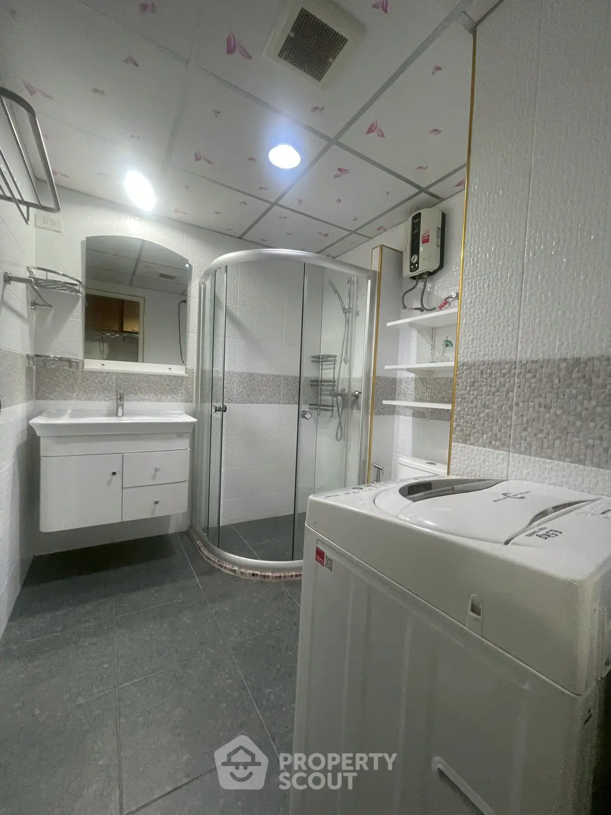 Modern bathroom with shower, washing machine, and sleek vanity in stylish apartment.