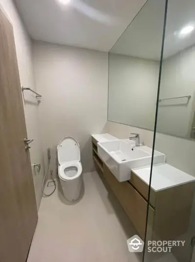 Sleek modern bathroom with large mirror and minimalist vanity, featuring clean lines and a bright, airy feel.