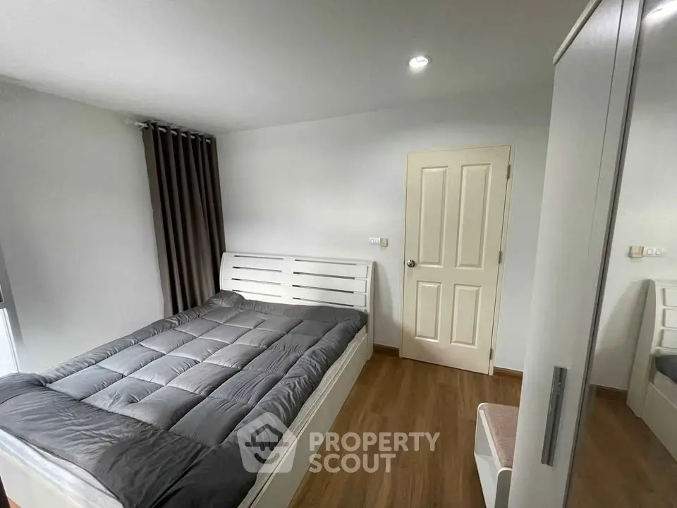 Modern bedroom with wooden flooring and minimalist design, featuring a cozy bed and sleek wardrobe.