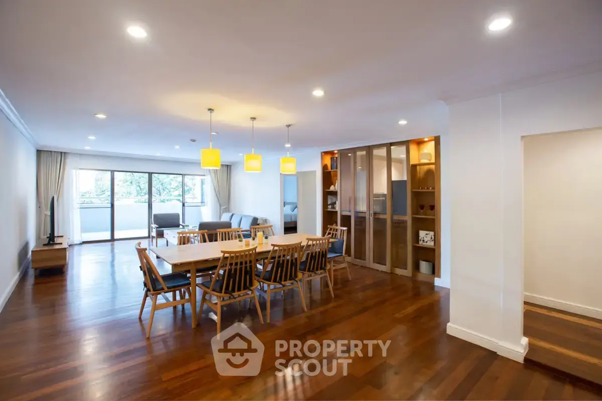 Spacious open-plan living and dining area with elegant wooden flooring and modern lighting.