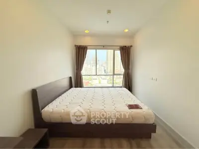 Spacious bedroom with city view and modern furnishings in high-rise apartment.