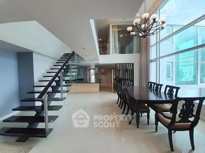 Luxurious open-plan dining area with elegant staircase and large windows