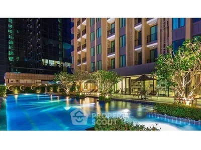 Luxurious apartment complex with stunning illuminated pool and lush greenery at night.