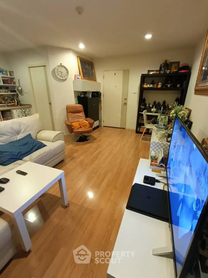 Cozy living room with modern decor and wooden flooring, featuring a comfortable seating area and entertainment setup.