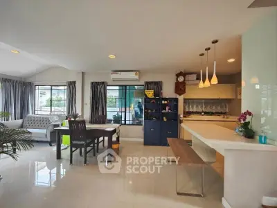 Spacious open-plan living room and kitchen with modern decor and ample natural light.