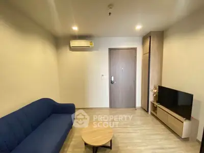 Modern living room with blue sofa, TV, and wooden flooring in a cozy apartment.