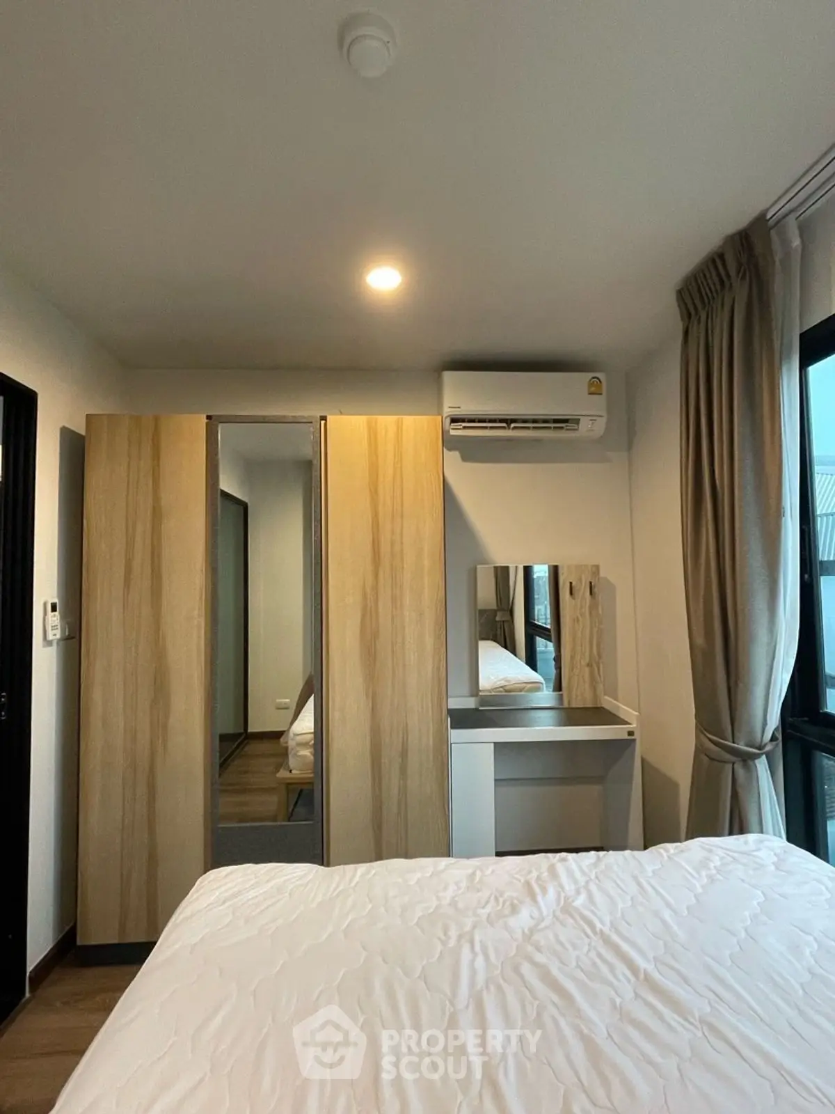 Cozy bedroom with modern wardrobe and air conditioning, perfect for comfortable living.