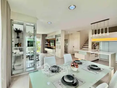Modern open-plan dining and living area with stylish decor and glass accents.