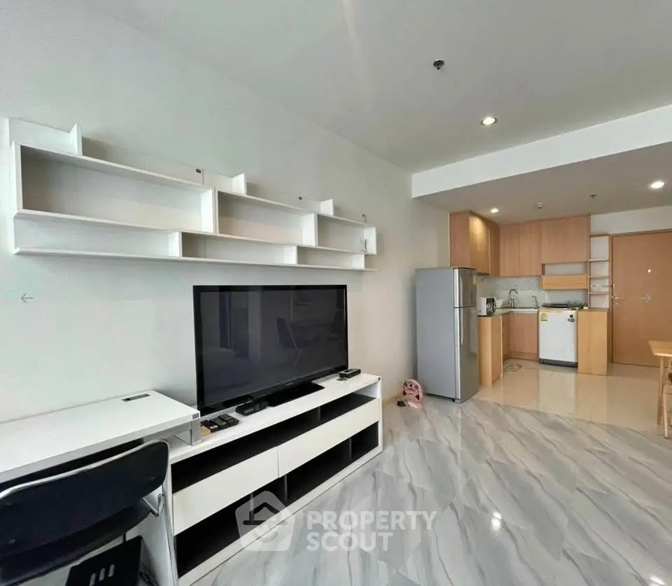 Modern open-plan living room with sleek kitchen and stylish shelving in a contemporary apartment.