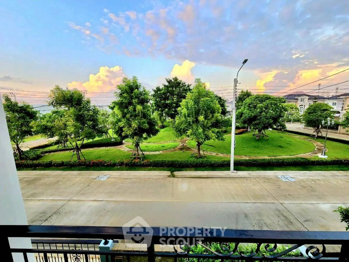 Stunning view from balcony overlooking lush green park and vibrant sky.
