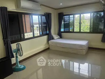 Spacious bedroom with large windows and air conditioning unit, offering ample natural light and comfort.