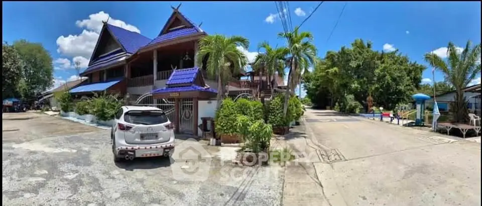 Charming traditional house with blue roof and lush greenery in serene neighborhood.
