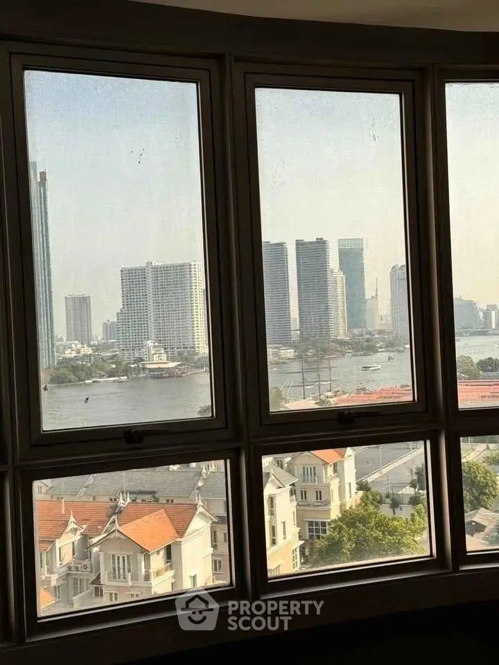 Stunning cityscape view from high-rise window overlooking river and skyline.