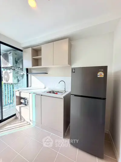 Modern kitchen with sleek cabinetry and stainless steel fridge in bright apartment