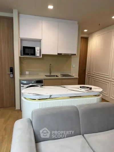 Modern compact kitchen with marble island and built-in appliances in cozy apartment.