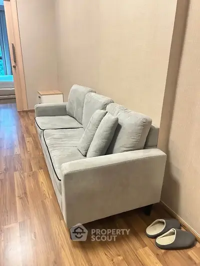 Cozy living room with modern gray sofa and wooden flooring, perfect for relaxation.
