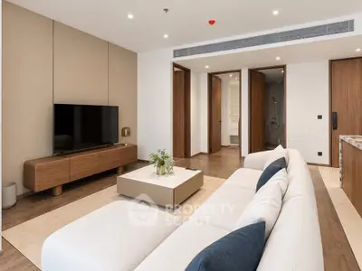 Modern living room with sleek furniture and open layout, featuring a large TV and stylish decor.