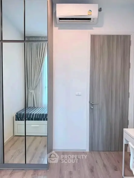 Modern bedroom with mirrored wardrobe and air conditioning in stylish apartment.