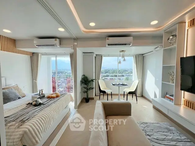Luxurious open-plan bedroom and living area with panoramic city views and modern decor.