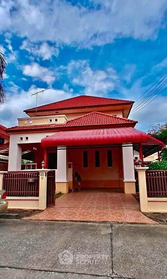 Charming two-story house with red roof and spacious driveway in a serene neighborhood.