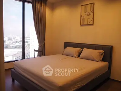 Spacious bedroom with large window offering city views, modern decor, and cozy ambiance.