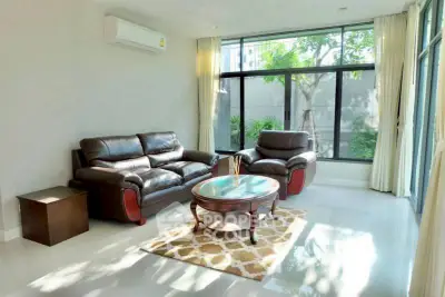Spacious living room with modern leather sofas and large windows offering natural light.