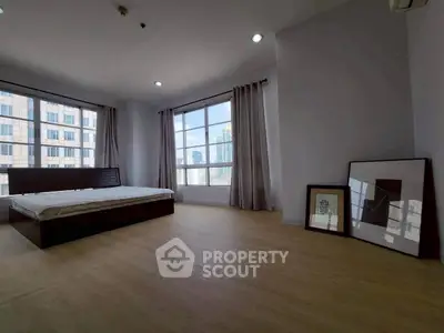 Spacious bedroom with large windows and city view in modern apartment