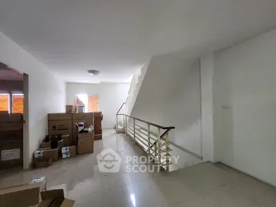 Spacious hallway with modern staircase and natural light, ideal for storage or renovation.