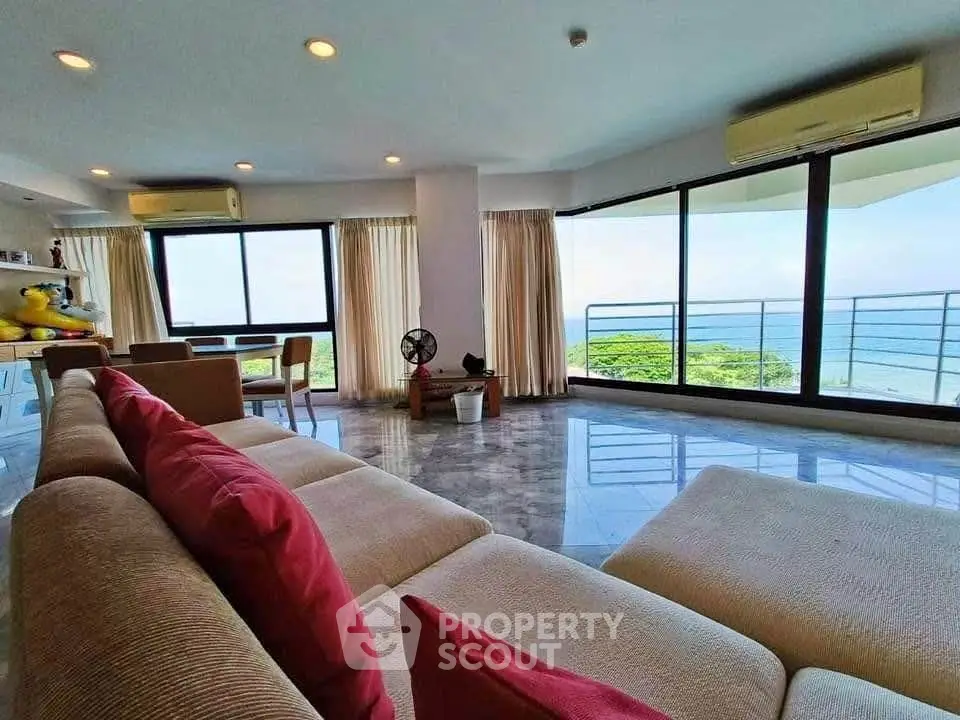 Spacious living room with ocean view and modern decor, featuring large windows and comfortable seating.