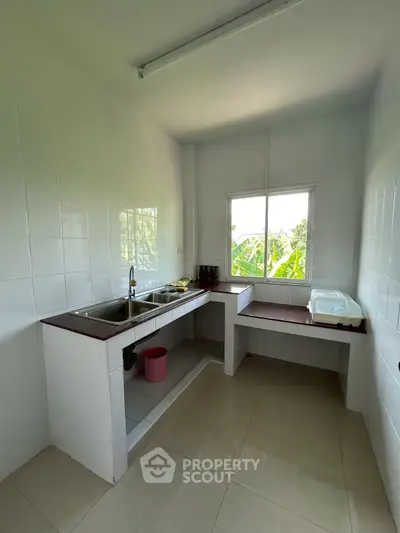 Bright and spacious kitchen with large window and modern fixtures, perfect for culinary enthusiasts.