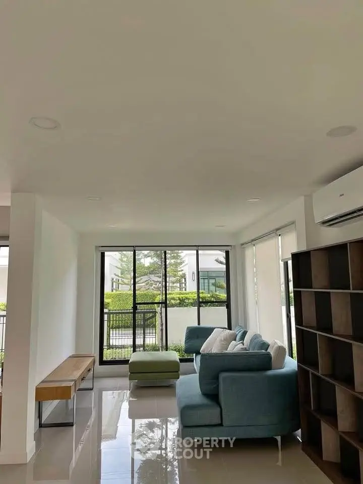 Modern living room with large windows and stylish furniture, offering a bright and inviting atmosphere.