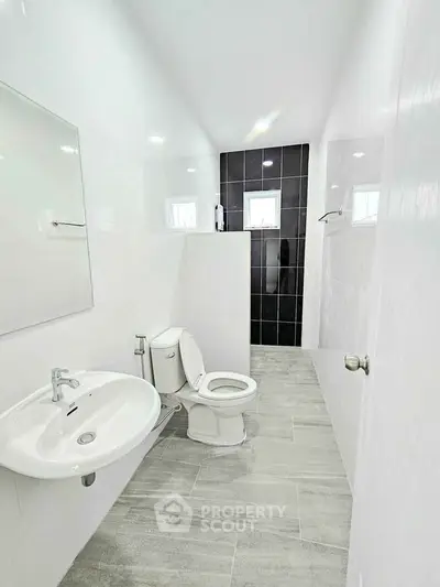 Modern bathroom with sleek design and tiled flooring, featuring a toilet and sink.