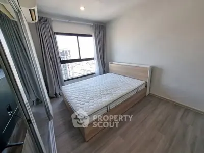 Modern bedroom with large window and minimalist design in high-rise apartment.