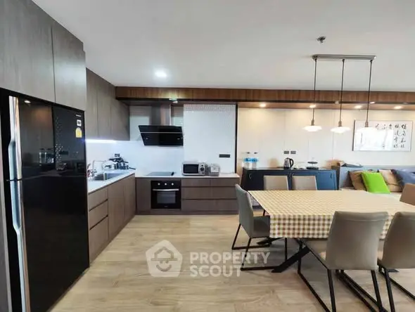 Modern kitchen with dining area, featuring sleek cabinetry and contemporary lighting.
