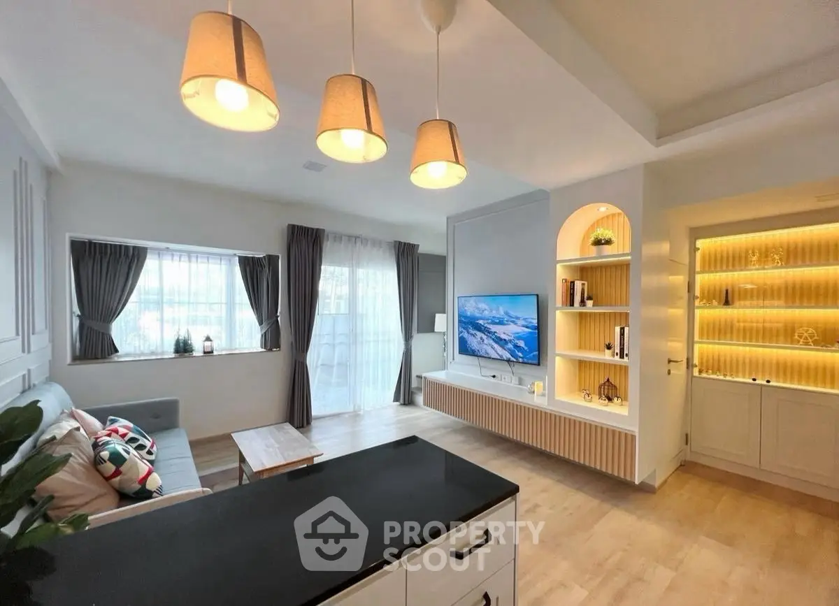 Modern living room with stylish lighting and built-in shelving, featuring a cozy seating area and large TV.