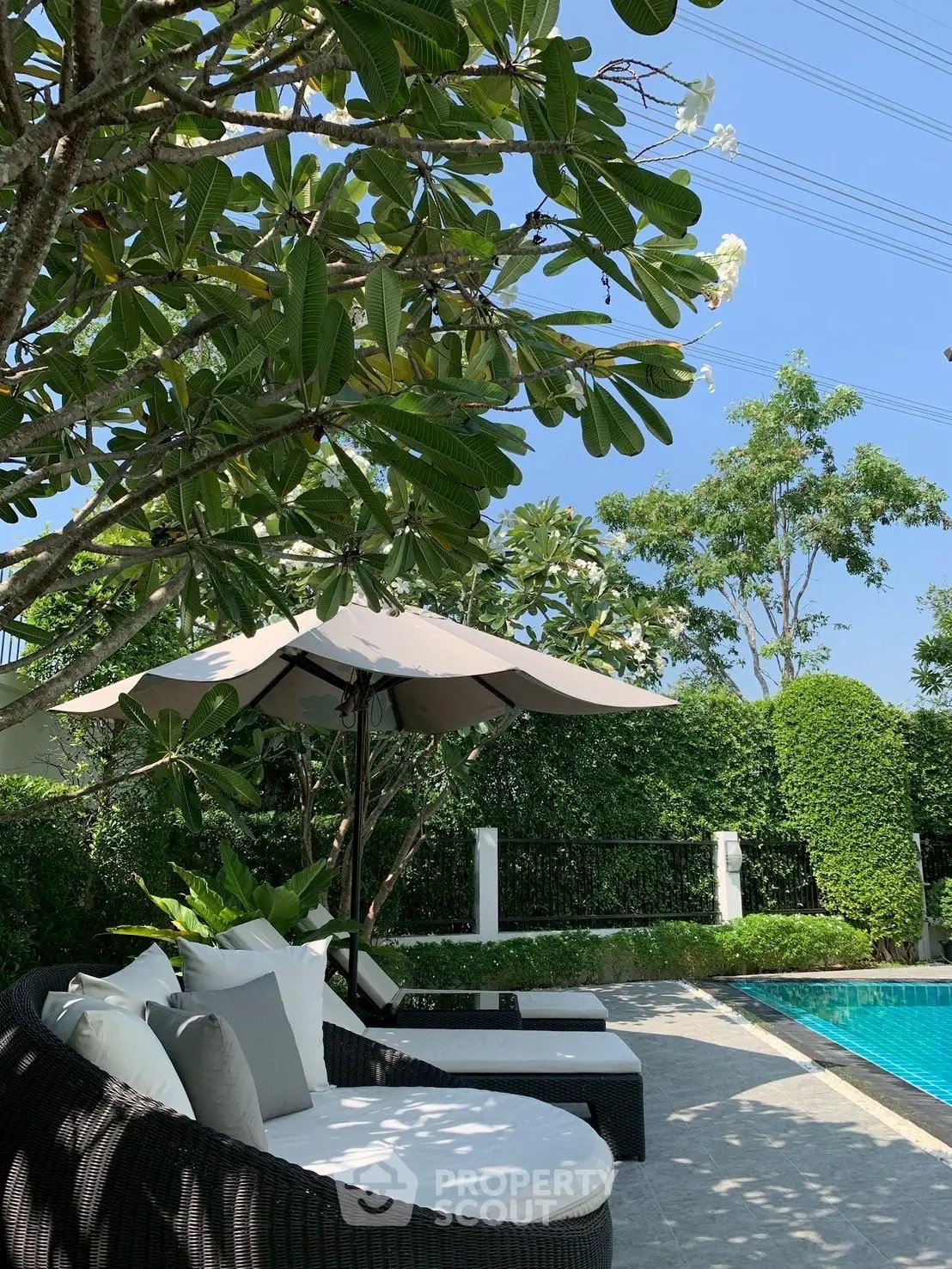 Luxurious outdoor pool area with stylish loungers and lush greenery, perfect for relaxation and entertainment.