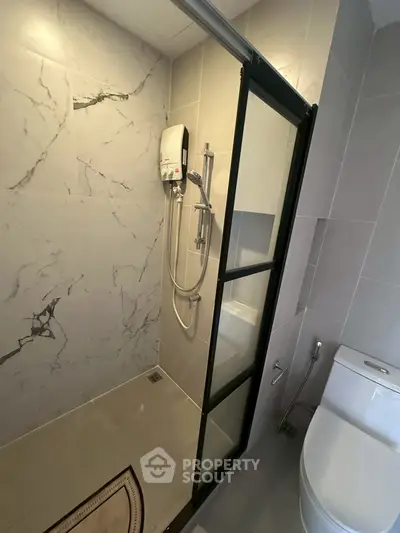 Modern bathroom with sleek shower and elegant marble tiles, perfect for a contemporary home.