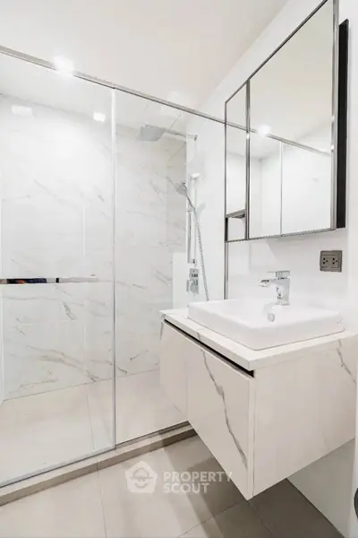 Modern bathroom with sleek design, featuring a glass shower and elegant vanity.