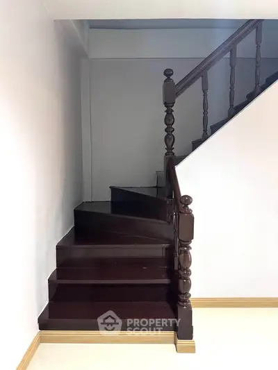 Elegant wooden staircase with polished dark wood finish in a modern home interior.