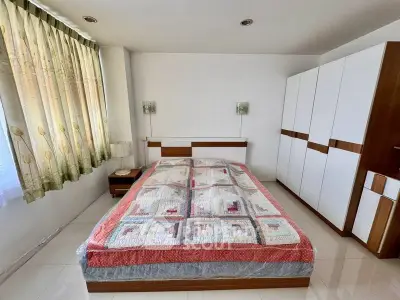 Spacious bedroom with modern wardrobe and large window for natural light.