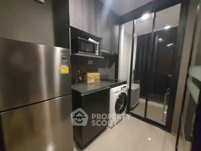 Modern kitchen with sleek appliances and washing machine in stylish condo unit.
