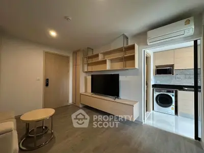 Modern living room with open kitchen, featuring sleek wooden furniture and built-in appliances.