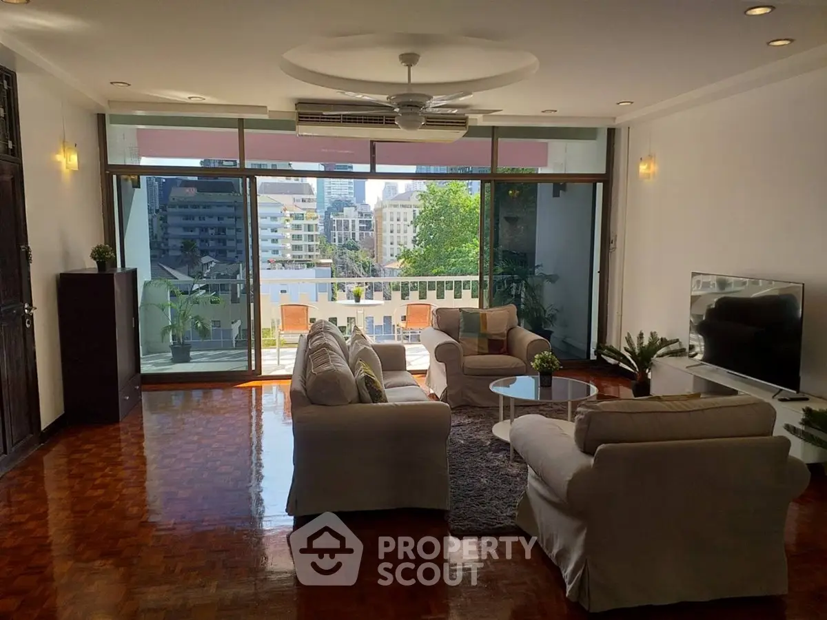 Spacious living room with large windows and city view, featuring cozy seating and modern decor.