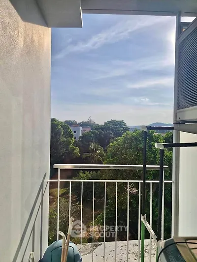 Charming balcony with lush green view and partial cityscape, perfect for relaxation.