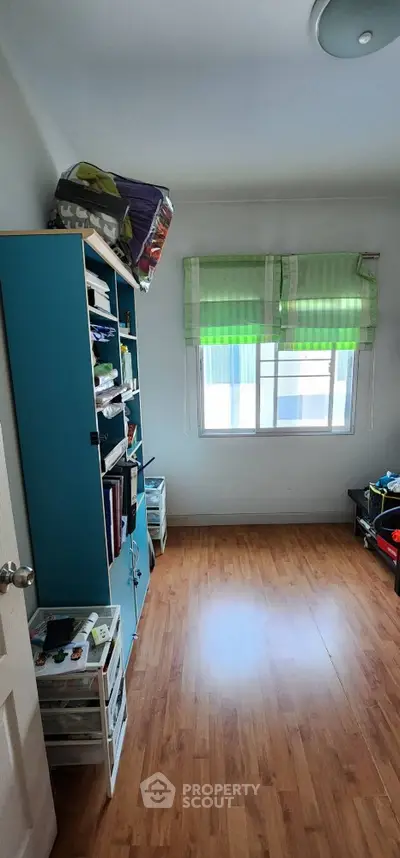 Cozy small room with wooden flooring and ample natural light from window.